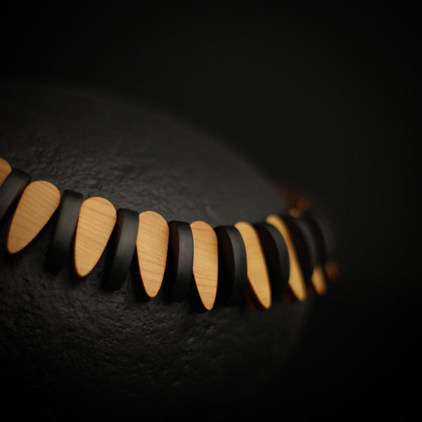 Trace - Close up detail of wooden necklace showing polished wood and black segments