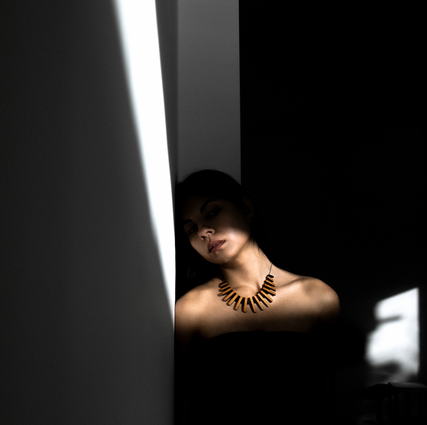 Model Alba wearing Cadence wooden necklace, photographed in shadows