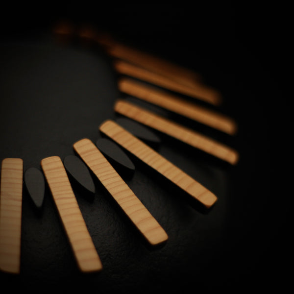 Close up detail of wooden necklace showing ebonised and natural wood sections. 